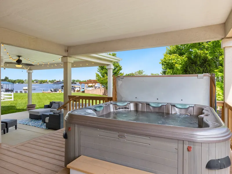 A hot tub on a covered back deck overlooking a lake