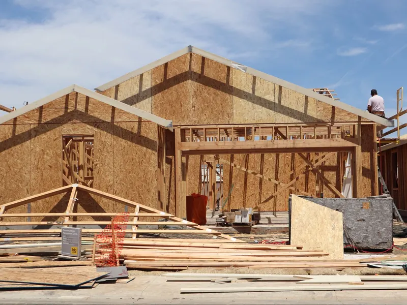 A new house framed in lumber on a construction lot under a blue sky