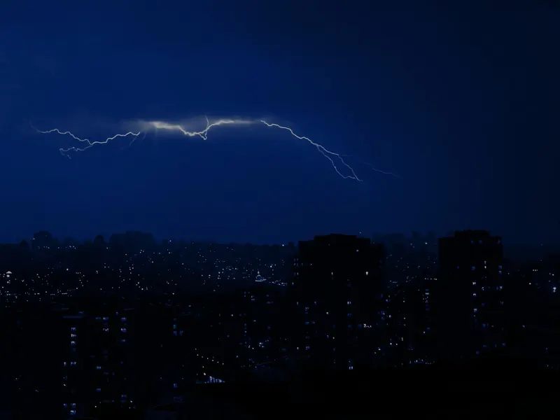 Lightning across a dark night sky above a town