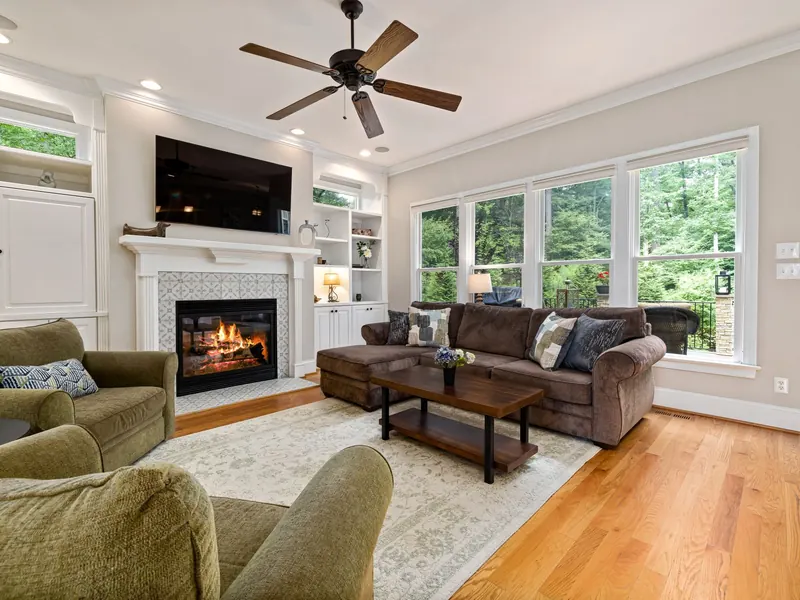 A living room with a ceiling fan, a fireplace and recessed lights