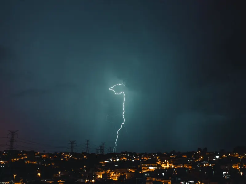 A lightning bolt striking over a town at night