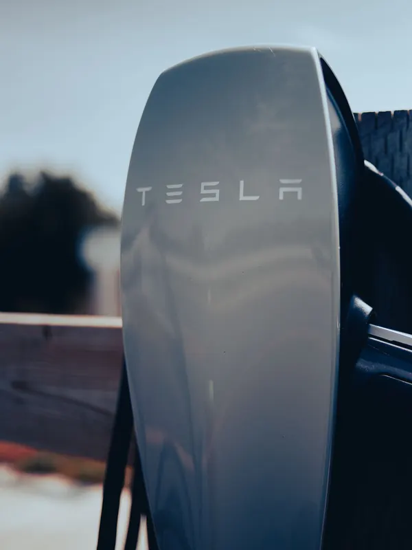 A wall-mounted Tesla home charging connector with its cable coiled